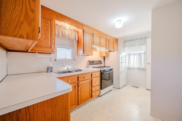 kitchen featuring white appliances, visible vents, light countertops, light floors, and a sink