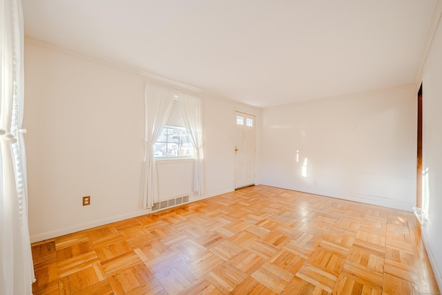 spare room with ornamental molding, visible vents, and baseboards