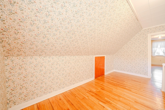 bonus room featuring wallpapered walls, wood-type flooring, baseboards, and vaulted ceiling