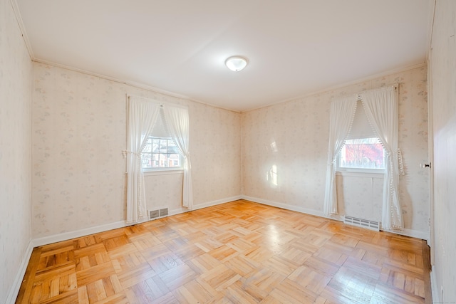 unfurnished room featuring a healthy amount of sunlight, visible vents, and wallpapered walls