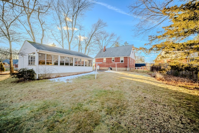 back of property with brick siding, fence, a sunroom, a yard, and a chimney