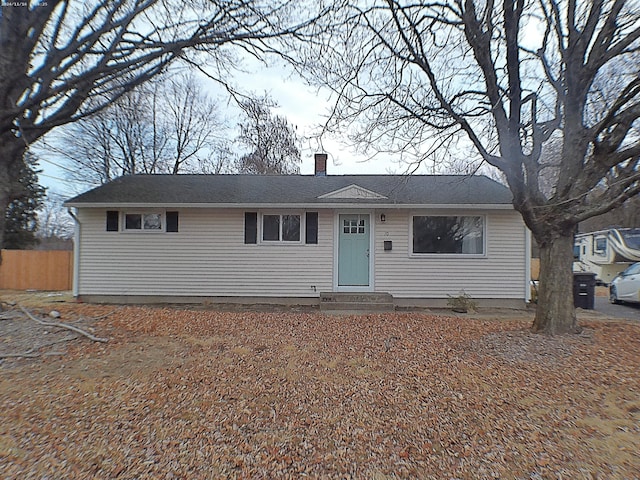 view of front facade with entry steps, a chimney, and fence