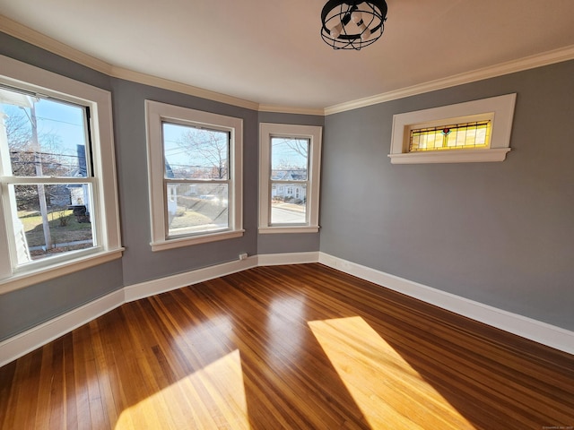 empty room featuring a healthy amount of sunlight, baseboards, dark wood-type flooring, and ornamental molding