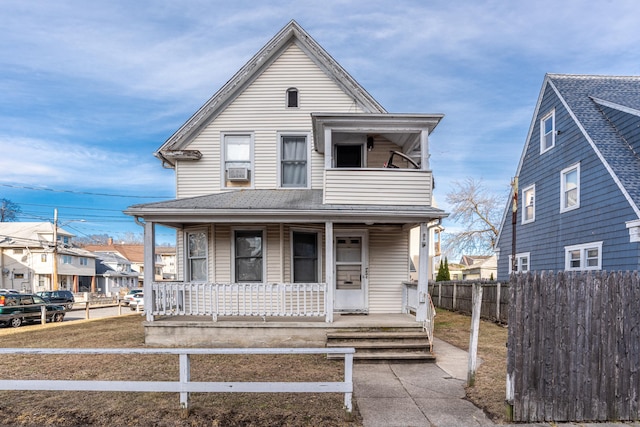 view of front of property featuring a shingled roof, covered porch, fence, and a balcony