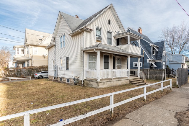 view of front facade featuring covered porch, fence, and a front yard