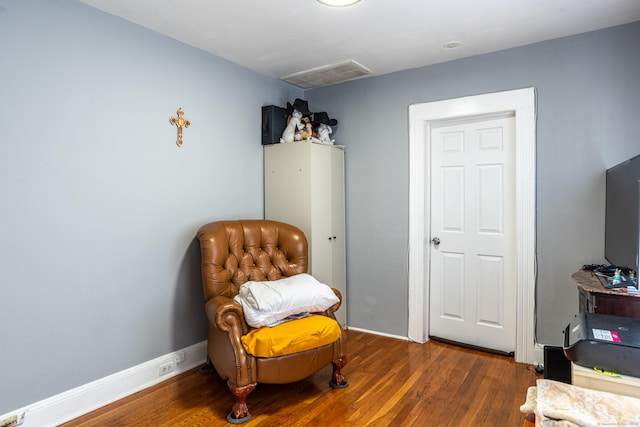 living area featuring wood finished floors, visible vents, and baseboards