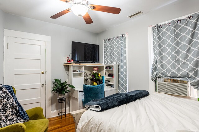 bedroom featuring ceiling fan, cooling unit, wood finished floors, visible vents, and baseboards