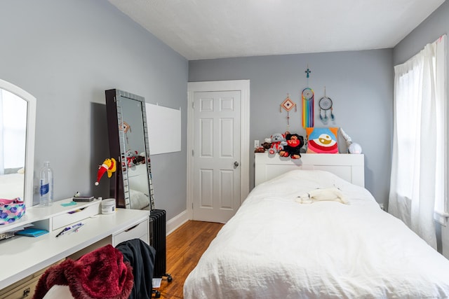 bedroom featuring radiator heating unit, dark wood finished floors, and baseboards