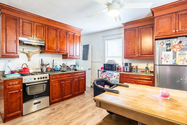 kitchen with stainless steel appliances, a ceiling fan, light stone countertops, light wood-type flooring, and under cabinet range hood