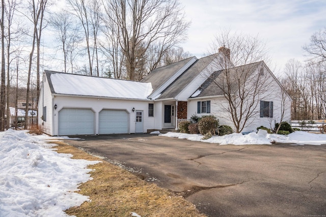 view of front of home with aphalt driveway, a chimney, and an attached garage