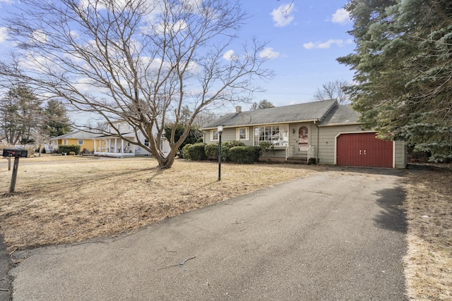 ranch-style home with a garage, a chimney, and aphalt driveway