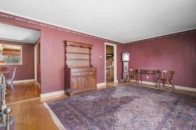 living room featuring crown molding, baseboards, hardwood / wood-style flooring, and wallpapered walls