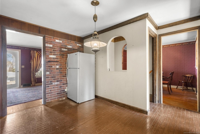 unfurnished dining area featuring baseboards, dark wood-type flooring, and wallpapered walls