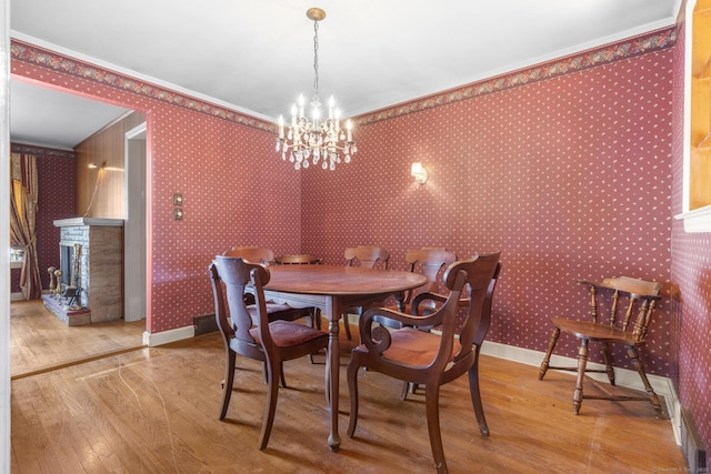 dining room with wallpapered walls, a fireplace, baseboards, and hardwood / wood-style flooring