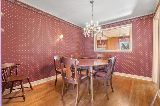 dining area featuring wood finished floors, a notable chandelier, baseboards, and wallpapered walls