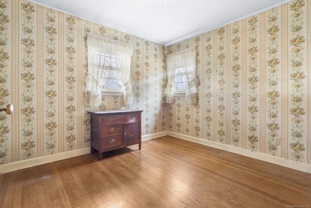 spare room featuring baseboards, wood finished floors, and wallpapered walls