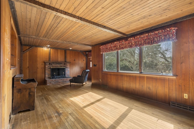 unfurnished room with wood ceiling, wood walls, a brick fireplace, and hardwood / wood-style flooring