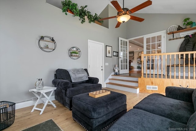 living area with high vaulted ceiling, wood finished floors, visible vents, and baseboards