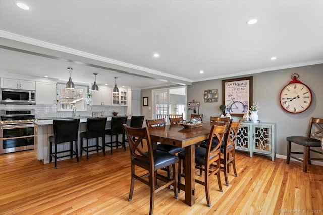 dining area featuring ornamental molding, light wood-type flooring, baseboards, and recessed lighting