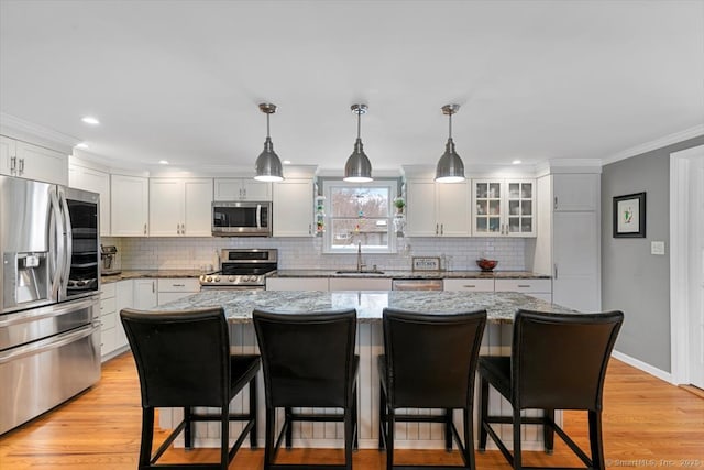 kitchen featuring light wood-style flooring, a kitchen bar, stainless steel appliances, and a sink