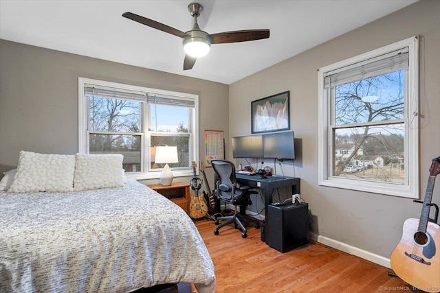 bedroom featuring a ceiling fan, multiple windows, light wood-style flooring, and baseboards