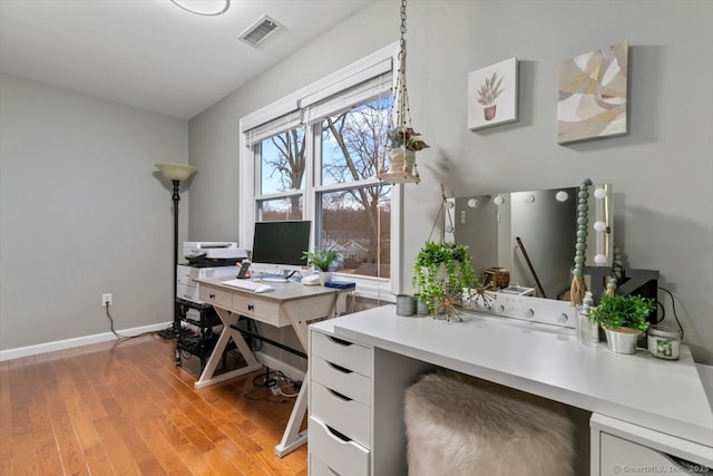 office space with light wood-style floors, baseboards, and visible vents