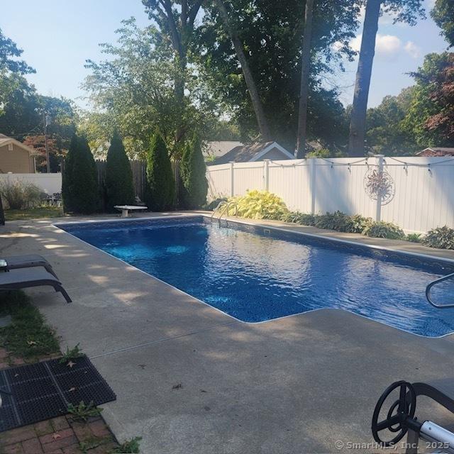 view of pool featuring a fenced in pool, a patio area, a fenced backyard, and a diving board