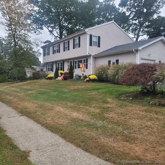 colonial house featuring a garage and a front lawn