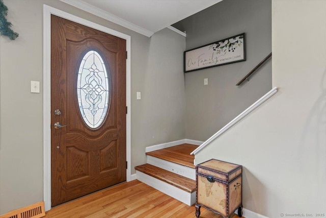 foyer entrance with visible vents, ornamental molding, wood finished floors, baseboards, and stairs