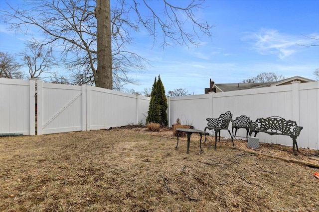 view of yard with a fenced backyard and a gate