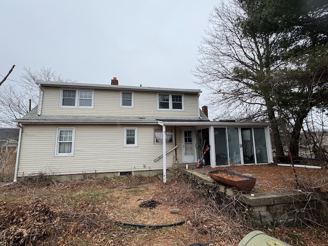 rear view of house with a chimney and a sunroom