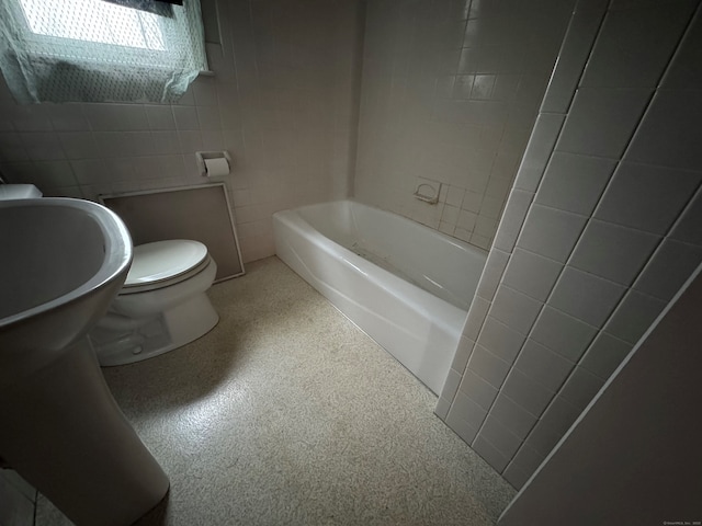 bathroom with toilet and tile walls