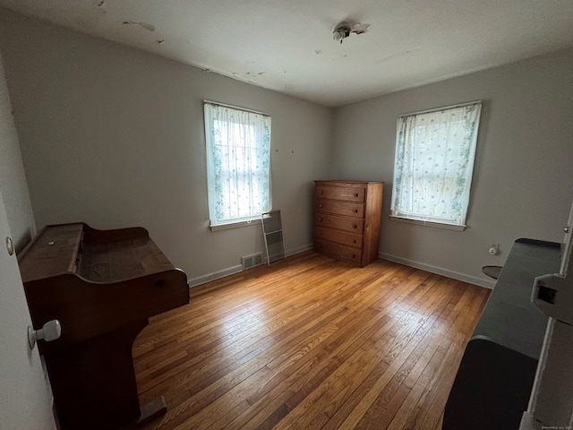 sitting room with visible vents, light wood-style flooring, and baseboards