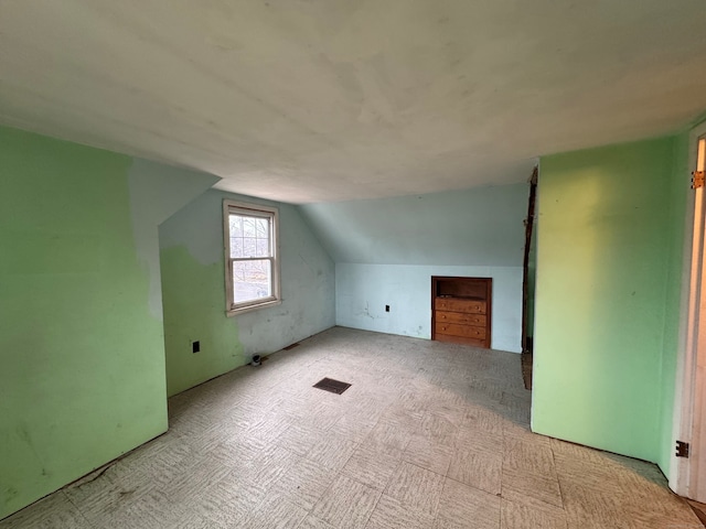 additional living space featuring vaulted ceiling and visible vents