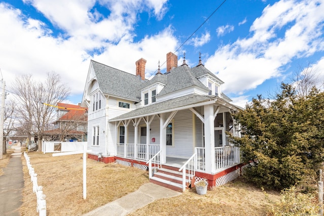 view of front of house featuring covered porch, a chimney, and roof with shingles