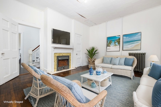 living room with a fireplace with flush hearth, radiator, stairs, and wood-type flooring