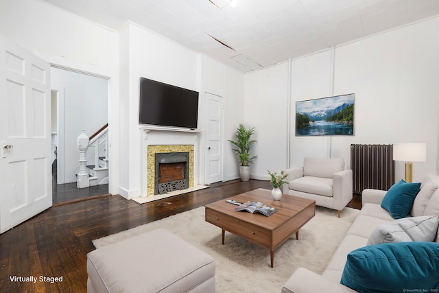 living room featuring hardwood / wood-style floors, stairway, radiator heating unit, and a fireplace