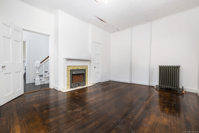 unfurnished living room with radiator, baseboards, stairway, a fireplace, and hardwood / wood-style flooring