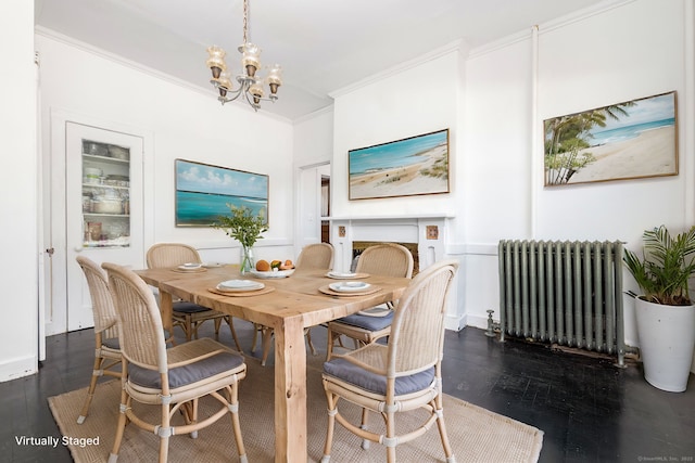 dining space with dark wood finished floors, radiator heating unit, a fireplace, crown molding, and a chandelier