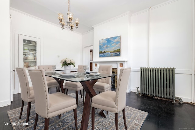 dining space featuring wood finished floors, a notable chandelier, ornamental molding, and radiator heating unit