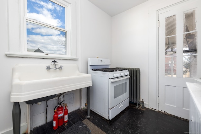 kitchen with white gas range, concrete flooring, and a sink