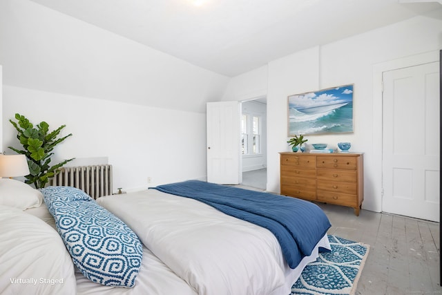 bedroom featuring light wood finished floors, radiator heating unit, and vaulted ceiling