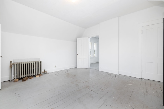 bonus room with vaulted ceiling, radiator, wood finished floors, and baseboards