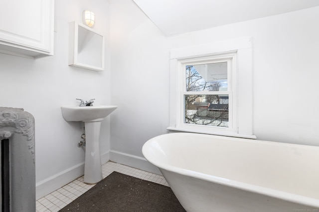 bathroom featuring tile patterned floors, baseboards, and a freestanding bath