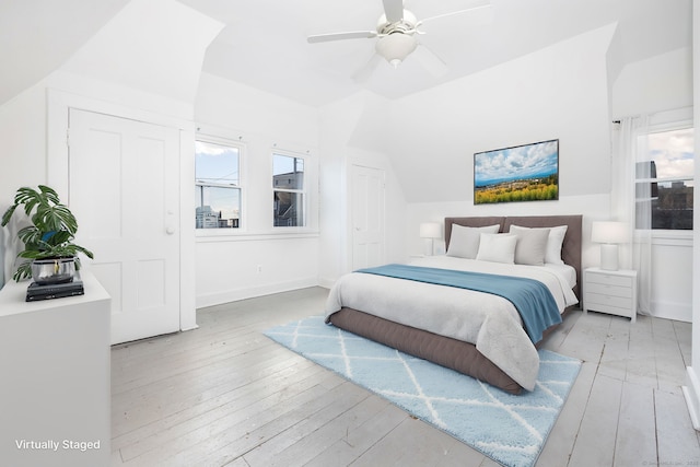 bedroom featuring a ceiling fan, multiple windows, light wood-style floors, and baseboards