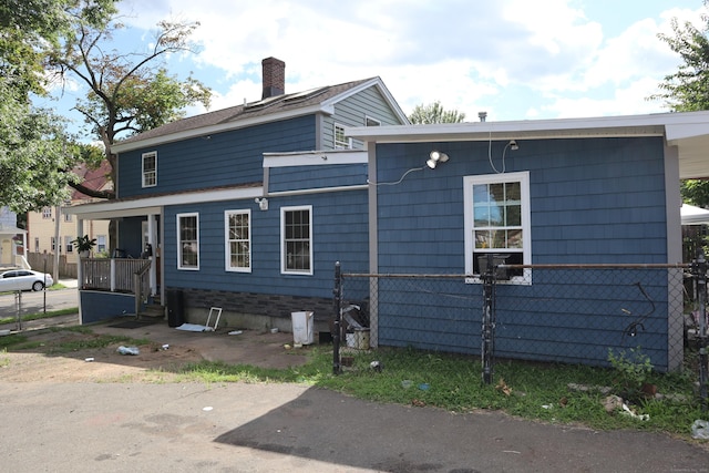 view of property exterior with a chimney and fence