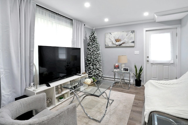 living area with recessed lighting, a baseboard heating unit, ornamental molding, wood finished floors, and baseboards