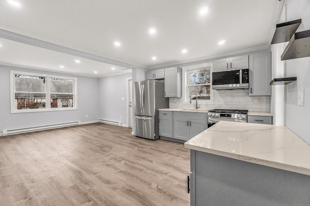 kitchen with a baseboard heating unit, appliances with stainless steel finishes, a sink, and gray cabinetry