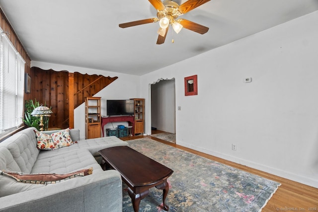 living area with light wood-type flooring, a ceiling fan, and baseboards