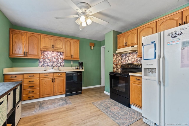 kitchen with light wood finished floors, under cabinet range hood, light countertops, black appliances, and a sink